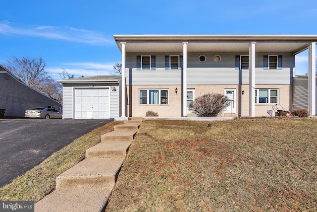 view of front of house featuring a front lawn, brick siding, a garage, and driveway