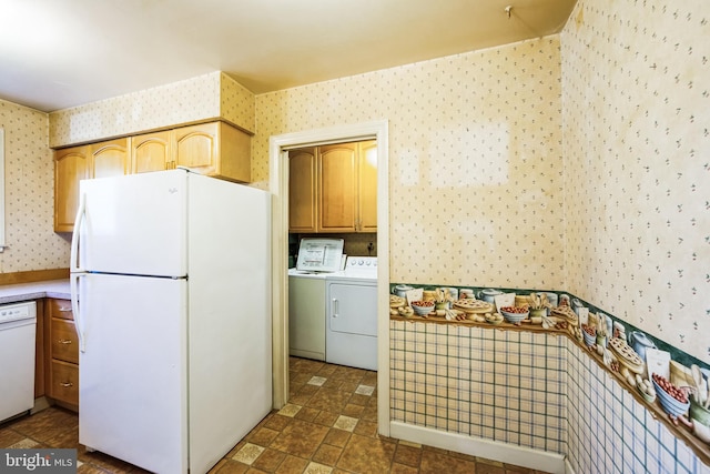 kitchen featuring stone finish flooring, wallpapered walls, washing machine and dryer, white appliances, and light countertops