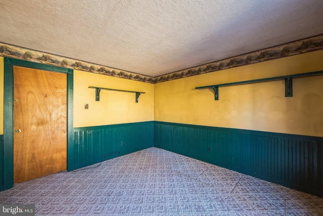 empty room with a wainscoted wall and a textured ceiling