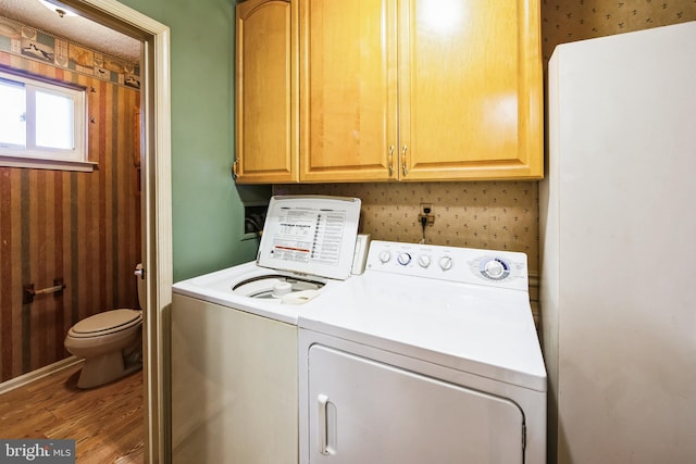 washroom featuring washer and clothes dryer, cabinet space, and wood finished floors