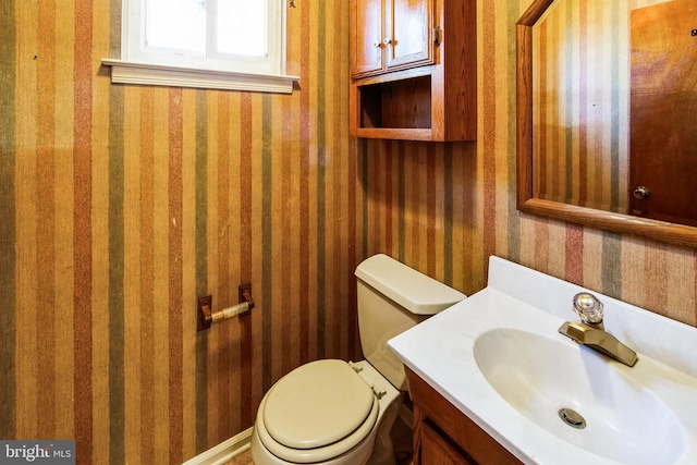 bathroom with wallpapered walls, toilet, and vanity