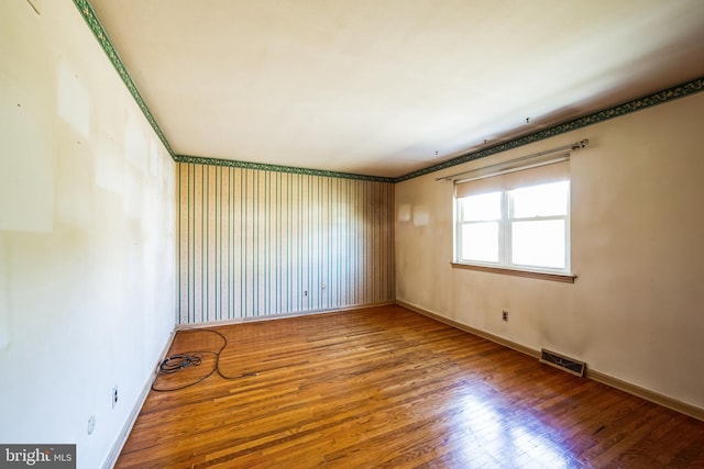 empty room featuring baseboards, visible vents, and wood-type flooring