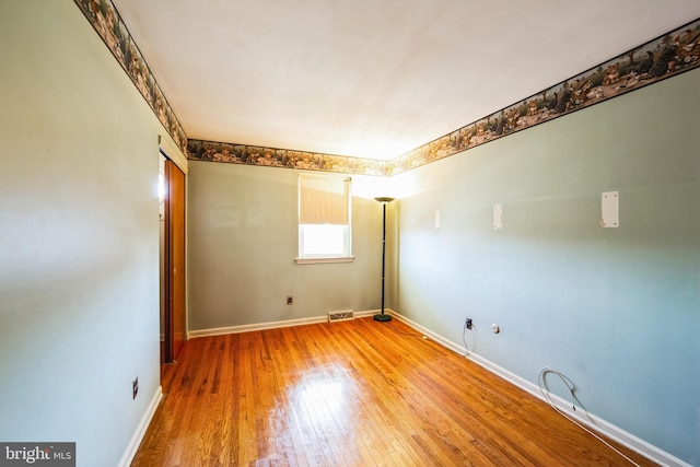 unfurnished room featuring light wood finished floors, visible vents, and baseboards