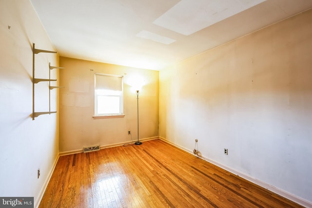 unfurnished room with hardwood / wood-style flooring, baseboards, and visible vents