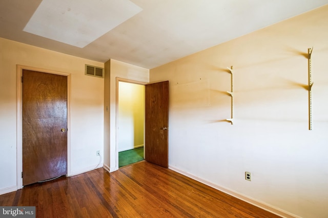 unfurnished bedroom featuring visible vents, baseboards, and wood finished floors