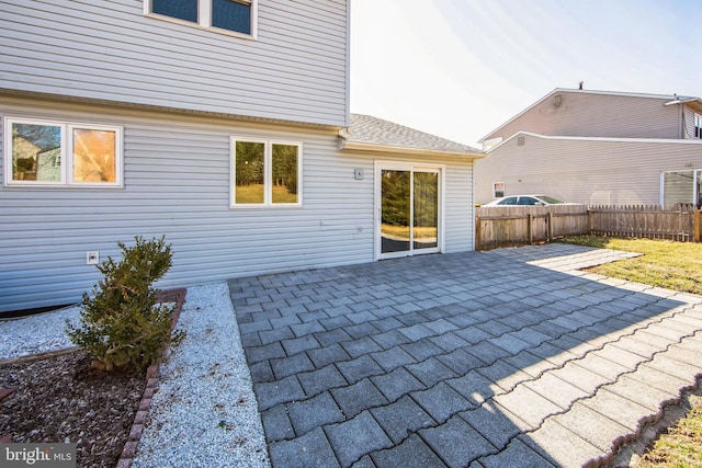 back of property with a patio, fence, and roof with shingles