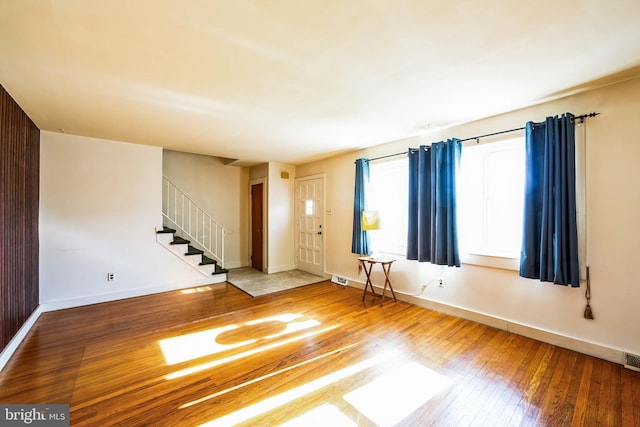 foyer with stairway, visible vents, baseboards, and wood-type flooring