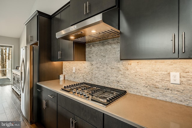 kitchen featuring extractor fan, light countertops, decorative backsplash, appliances with stainless steel finishes, and dark cabinetry