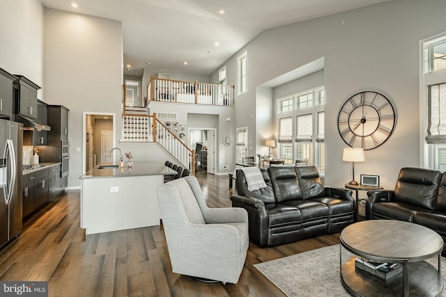 living area featuring baseboards, dark wood finished floors, recessed lighting, stairs, and a towering ceiling