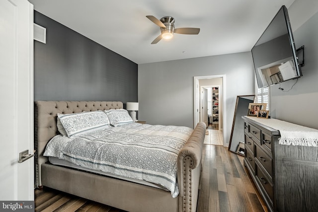 bedroom featuring visible vents, dark wood-type flooring, ceiling fan, and a spacious closet