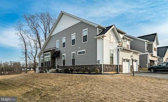 exterior space featuring central AC unit, a garage, a yard, stone siding, and driveway