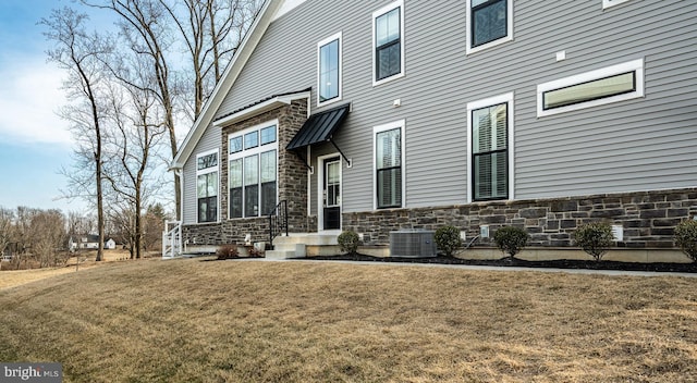 exterior space with stone siding, a lawn, and central AC unit