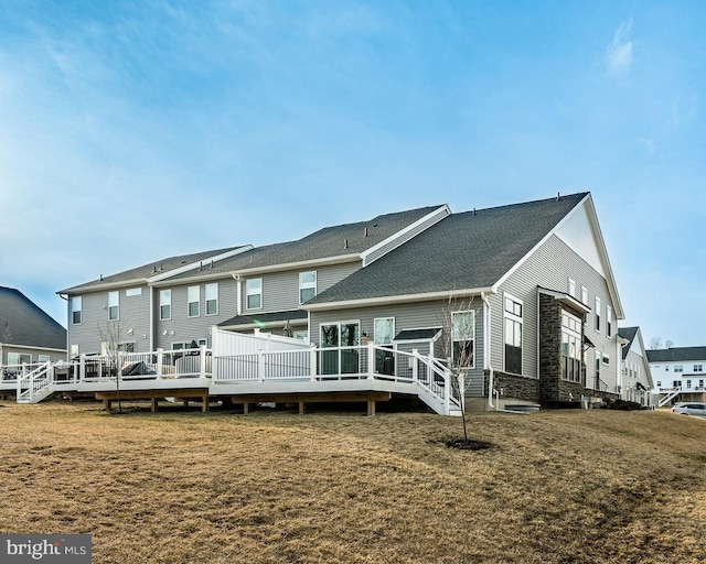 back of property featuring a wooden deck and a yard