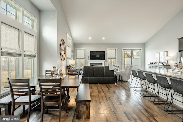 dining room featuring dark wood-style floors, recessed lighting, a fireplace, and high vaulted ceiling