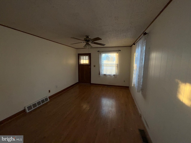 unfurnished room featuring baseboards, wood finished floors, visible vents, and a textured ceiling