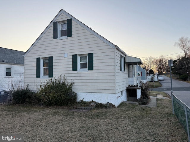 property exterior at dusk with a yard and fence