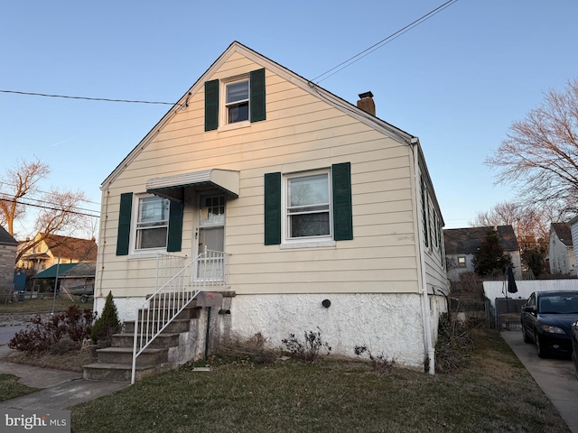 bungalow featuring a chimney and a front yard