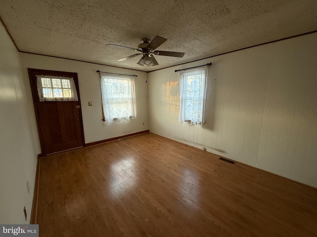 foyer entrance featuring visible vents, ceiling fan, a textured ceiling, crown molding, and light wood-type flooring