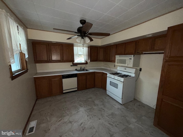 kitchen featuring visible vents, light countertops, brown cabinets, white appliances, and a sink