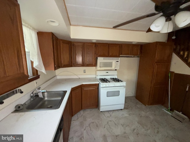 kitchen featuring white appliances, ceiling fan, a sink, light countertops, and brown cabinets