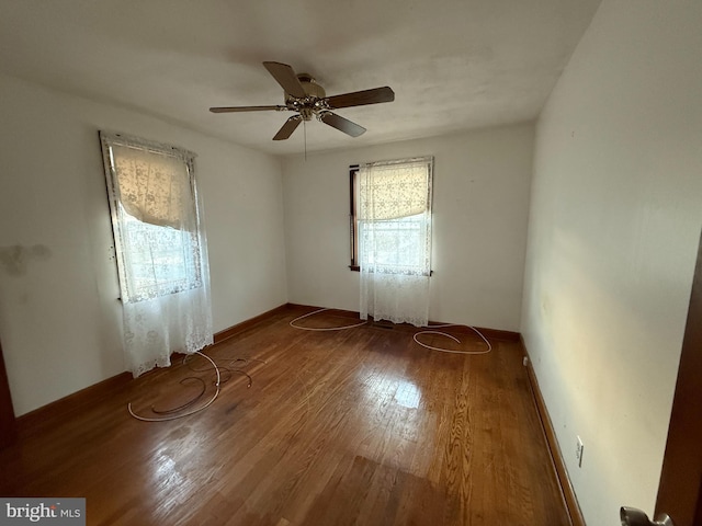 unfurnished room with baseboards, wood finished floors, and a ceiling fan