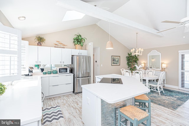 kitchen featuring a center island, freestanding refrigerator, a breakfast bar area, light countertops, and white microwave