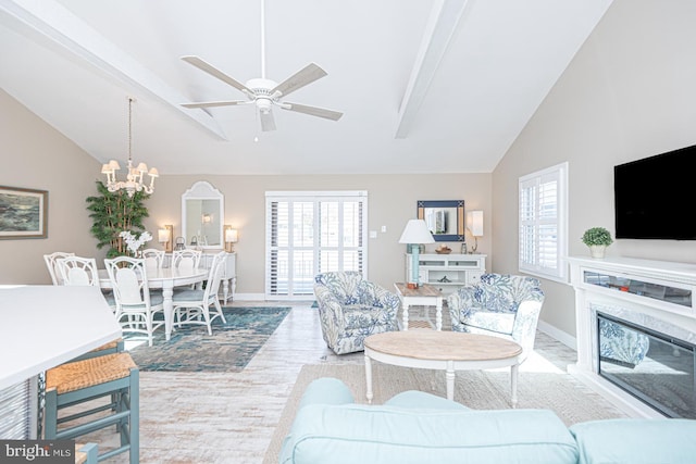 living area featuring ceiling fan with notable chandelier, wood finished floors, a premium fireplace, baseboards, and vaulted ceiling with beams