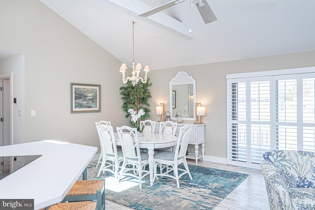 dining space featuring ceiling fan with notable chandelier, wood finished floors, baseboards, and high vaulted ceiling