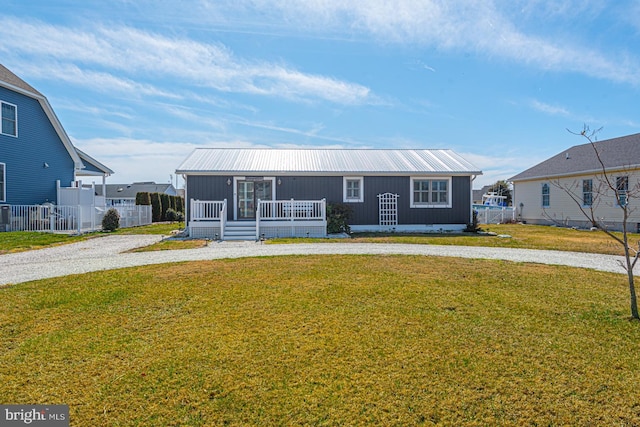 view of front of house featuring metal roof, a front lawn, and fence