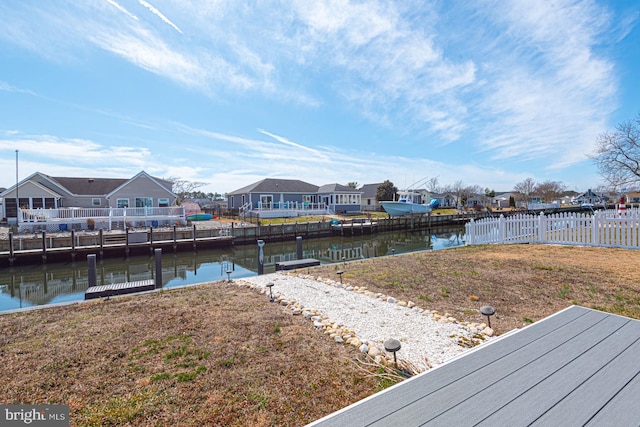 dock area featuring a yard, fence, a residential view, and a water view