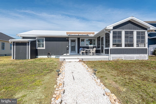 view of front of home featuring an outbuilding, a storage unit, a front lawn, and a sunroom