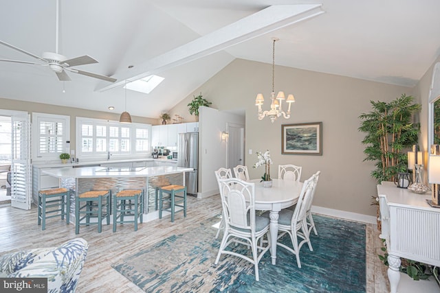 dining room with light wood-style flooring, ceiling fan with notable chandelier, baseboards, and high vaulted ceiling