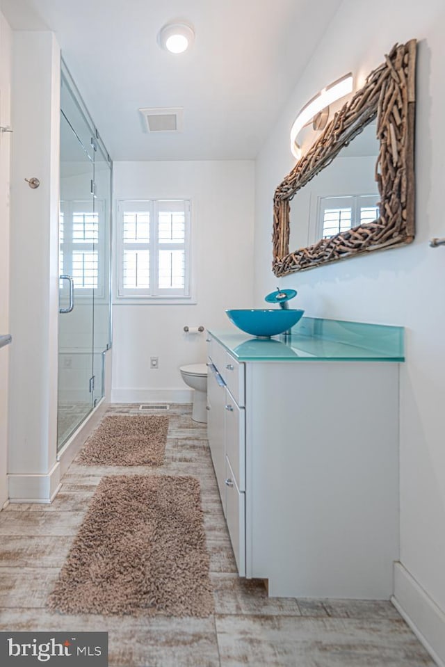 bathroom with visible vents, toilet, a stall shower, wood finished floors, and vanity