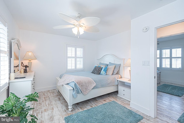 bedroom featuring baseboards, multiple windows, and light wood finished floors