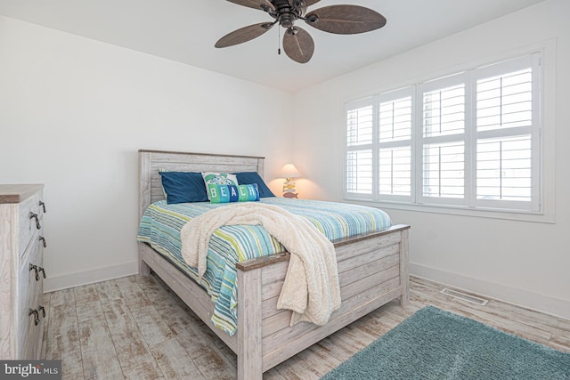 bedroom with light wood finished floors, visible vents, a ceiling fan, and baseboards