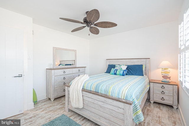 bedroom featuring light wood-style flooring, a ceiling fan, and baseboards