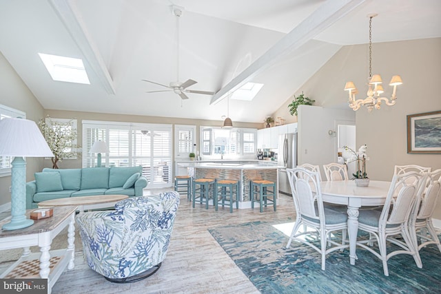 dining area with high vaulted ceiling, a skylight, ceiling fan, light wood-style floors, and beamed ceiling