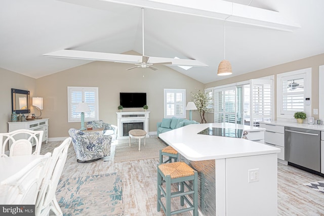 kitchen featuring a breakfast bar area, a fireplace, light countertops, dishwasher, and ceiling fan