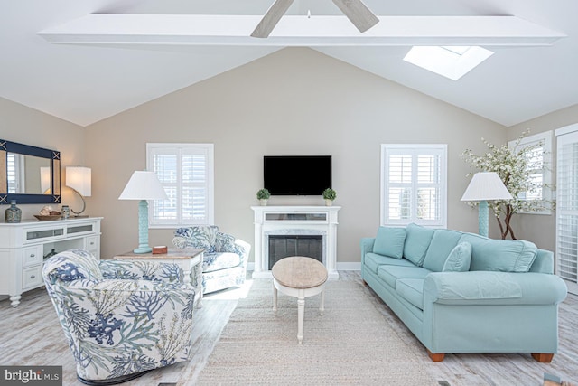 living area with a wealth of natural light, vaulted ceiling with skylight, a fireplace, and light wood finished floors