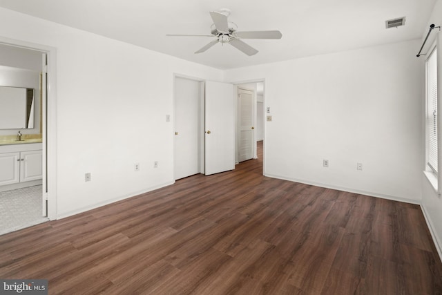 unfurnished bedroom with a sink, baseboards, ensuite bath, and wood finished floors