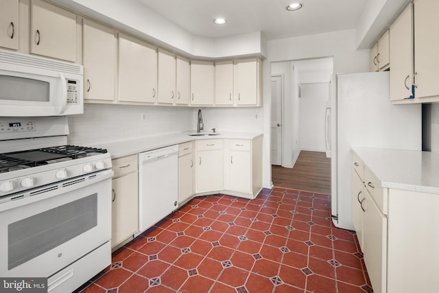 kitchen featuring backsplash, white appliances, light countertops, and a sink