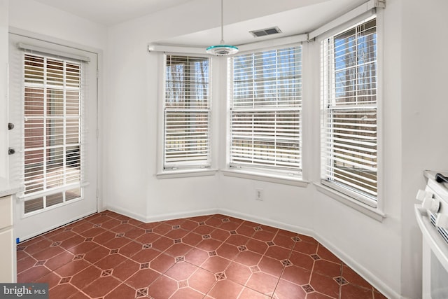 unfurnished dining area with visible vents, a healthy amount of sunlight, and baseboards