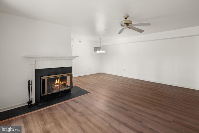 unfurnished living room featuring ceiling fan, baseboards, wood finished floors, and a glass covered fireplace