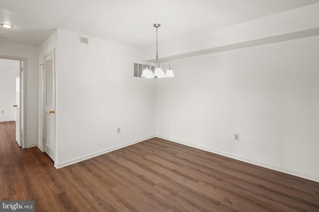 unfurnished dining area featuring an inviting chandelier, wood finished floors, baseboards, and visible vents