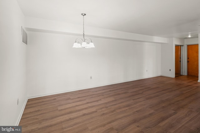 spare room featuring visible vents, baseboards, an inviting chandelier, and wood finished floors