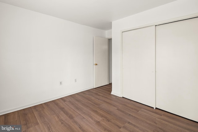 unfurnished bedroom with wood finished floors, a closet, and baseboards