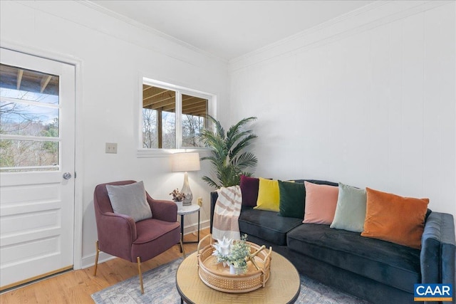 living area with crown molding, wood finished floors, and baseboards