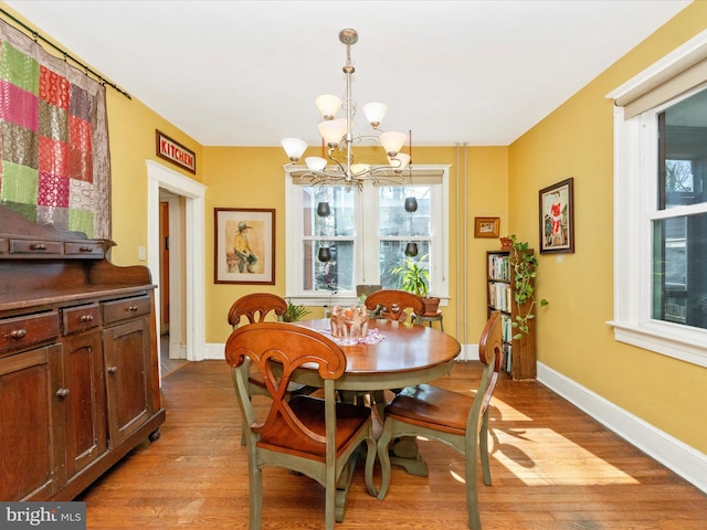 dining area featuring baseboards, light wood-style floors, and an inviting chandelier