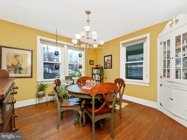 dining space with an inviting chandelier, light wood-type flooring, and baseboards