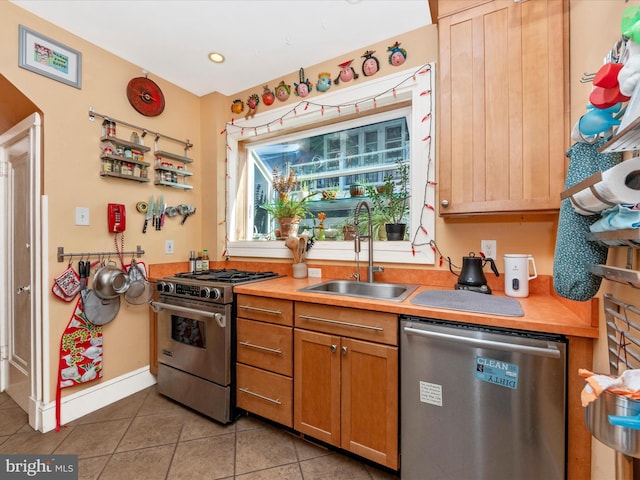 kitchen featuring a sink, stainless steel appliances, baseboards, and light tile patterned floors